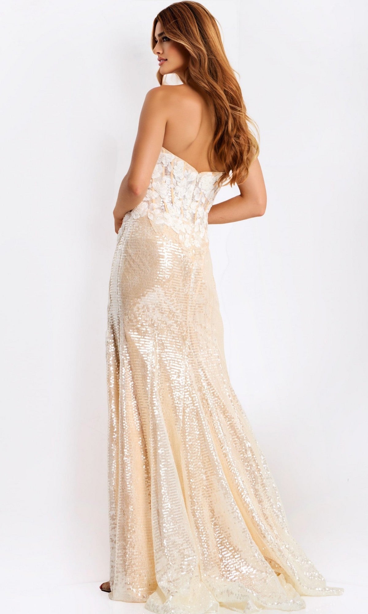 A woman with long hair faces away against a plain white background, wearing the floor-length, light-colored Jovani 49362 long prom dress with shimmering sequins and a strapless design.